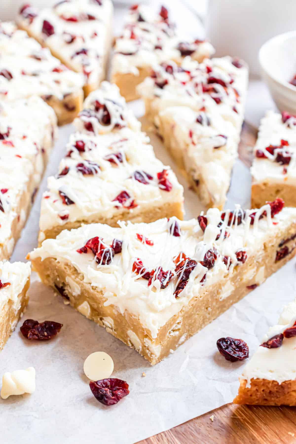 Cranberry bliss bars cut into triangles on parchment paper.