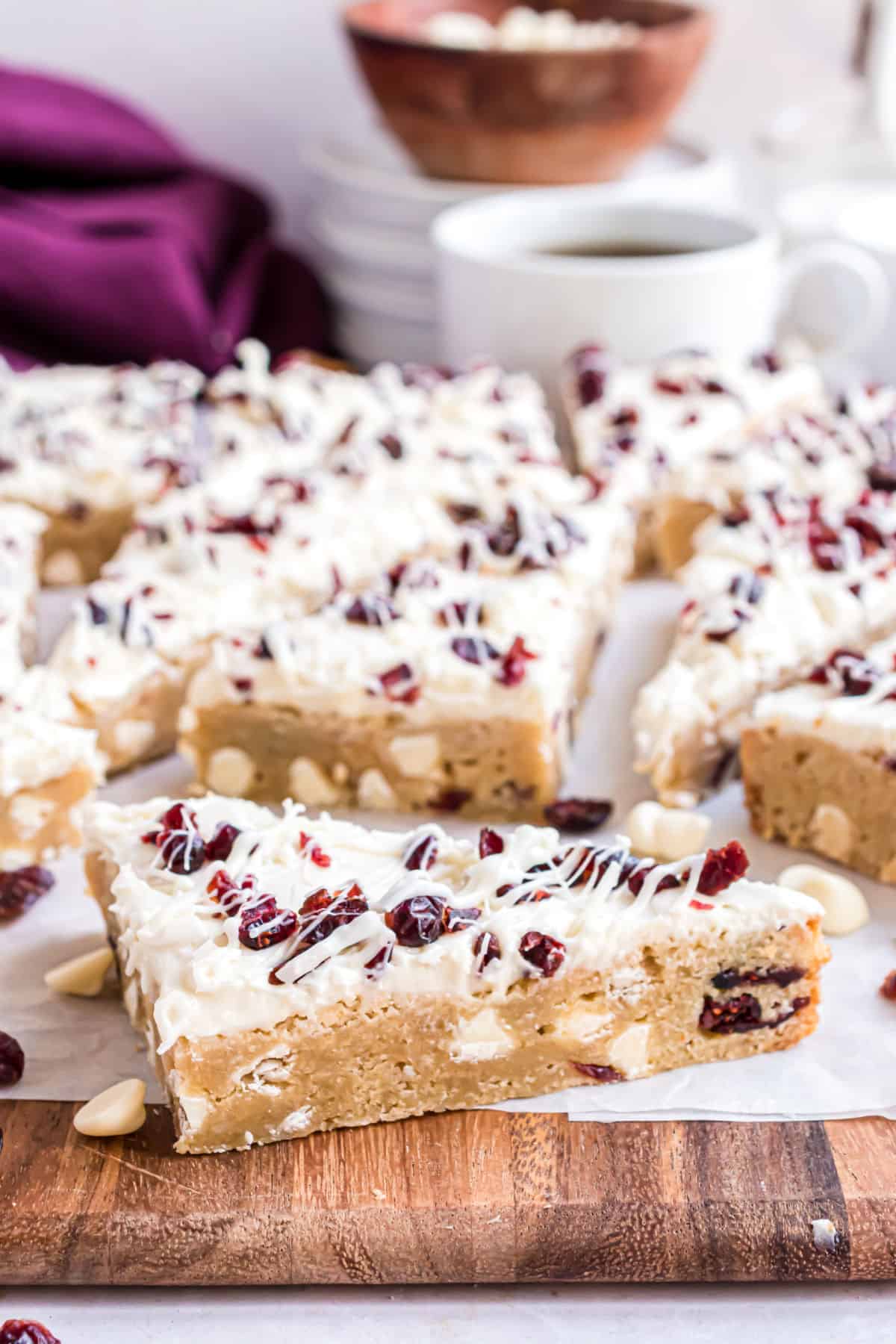 Cranberry bliss bars on a wooden cutting board.