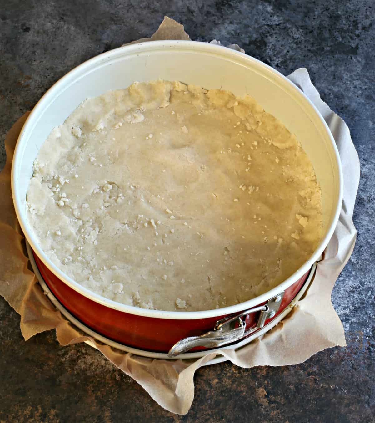 Shortbread cookie dough in bottom of springform pan.