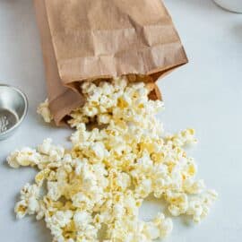 Cooked popcorn falling out of a brown paper bag.