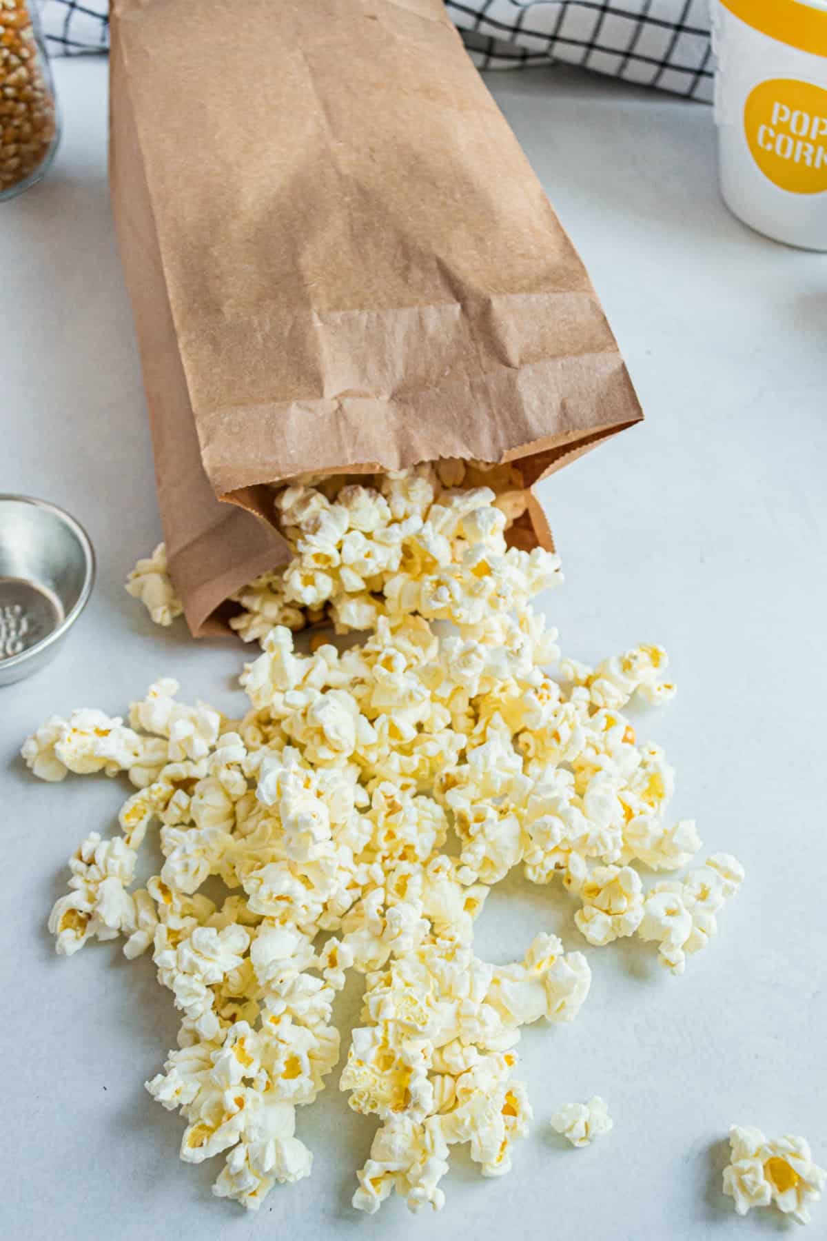 Cooked popcorn falling out of a brown paper bag.