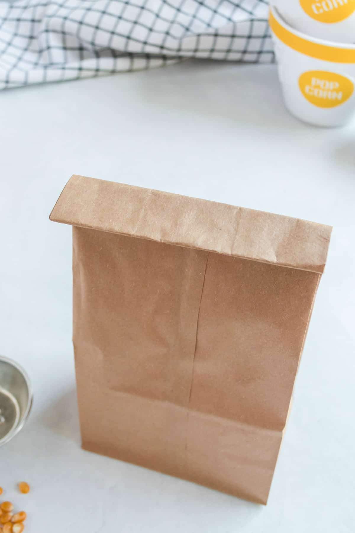 Brown paper bag folded over with popcorn inside.