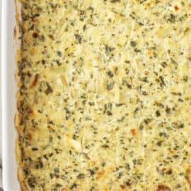 Baked spinach artichoke dip in square white baking dish.