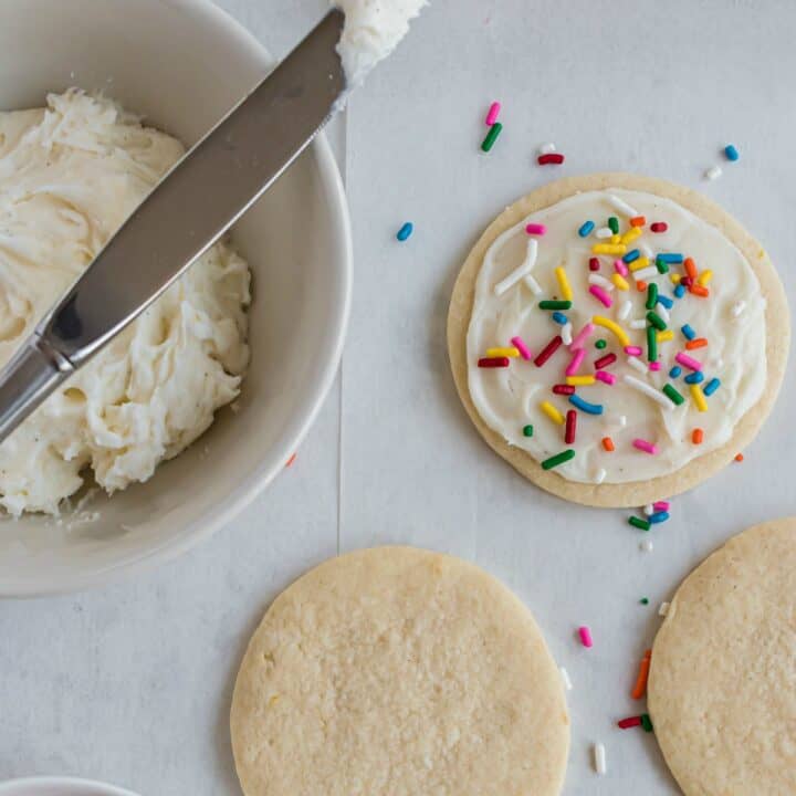 Sugar cookie being frosted with vanilla bean sugar cookie frosting.
