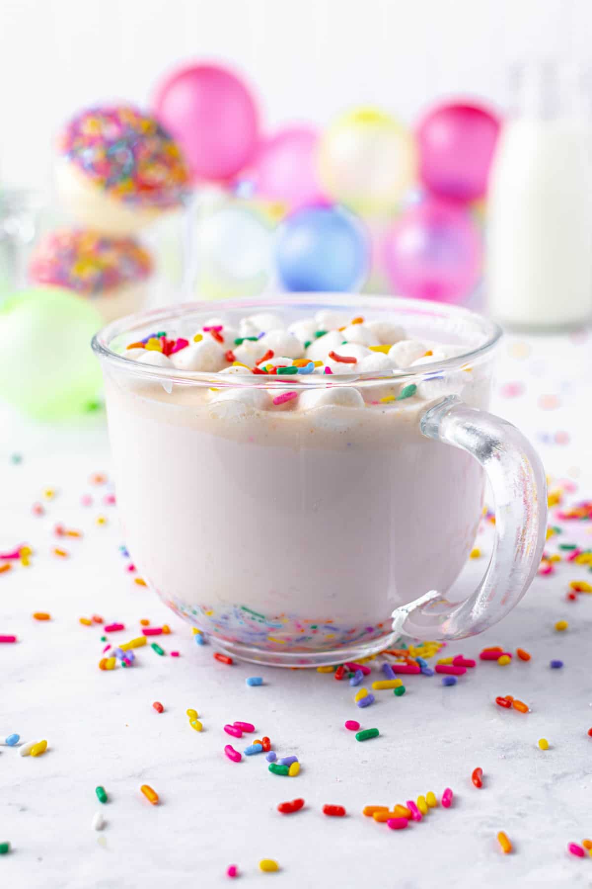 Hot cocoa bomb in mug of warm milk with sprinkles.