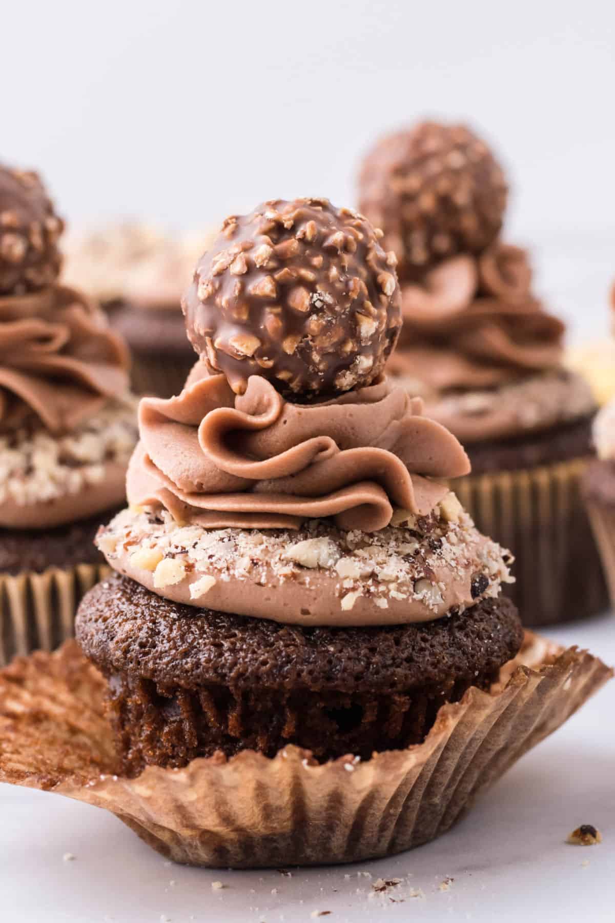 Unwrapped chocolate cupcake topped with hazelnuts, nutella buttercream, and a ferrero rocher chocolate.