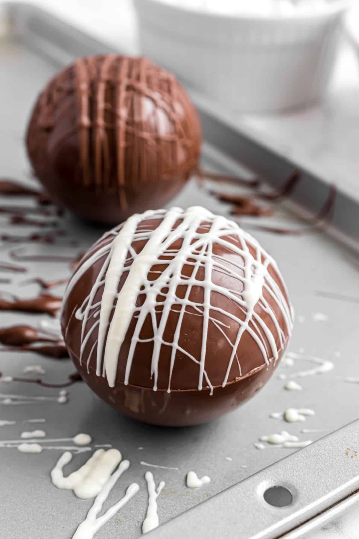 White chocolate drizzled on top of dark chocolate hot cocoa bombs.