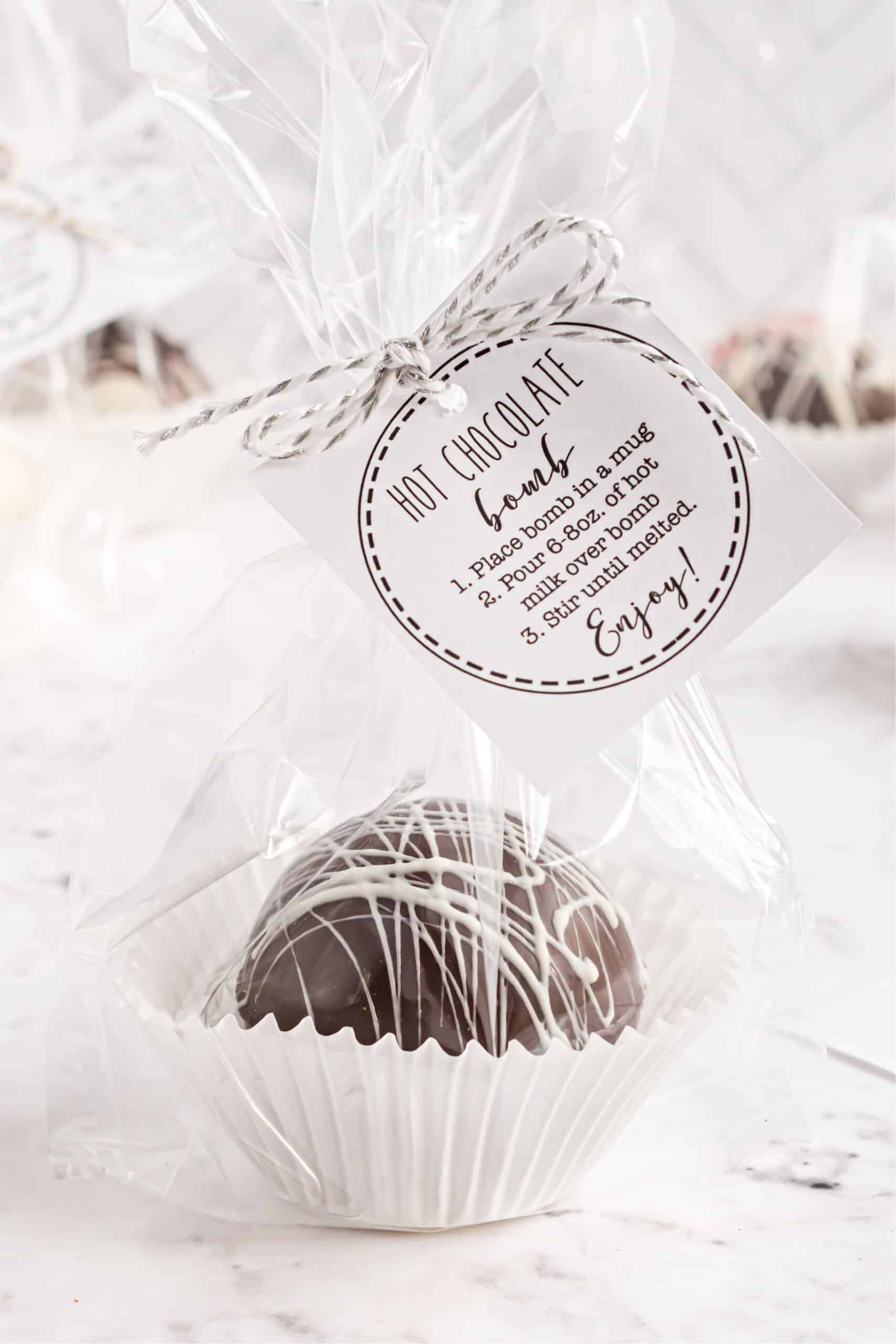 Hot chocolate bomb wrapped in clear cellophane with a tag attached.