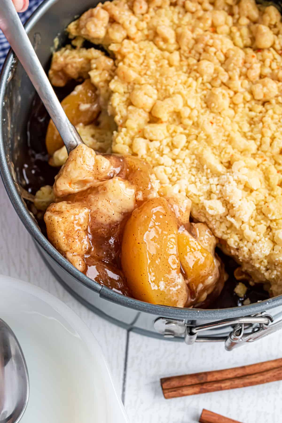 Scoop of peach cobbler being removed from springform pan.