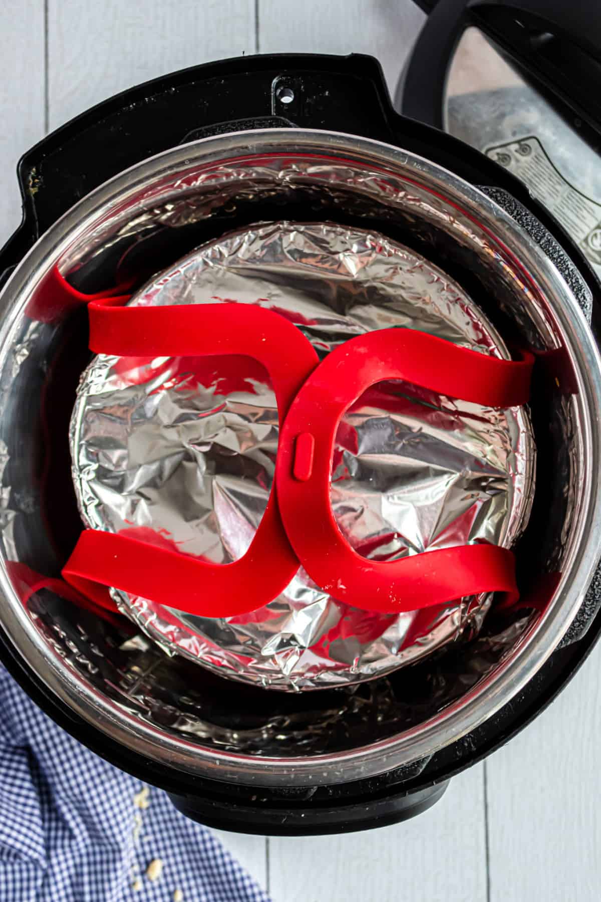 Peach cobbler wrapped in foil on a red sling inside a pressure cooker.