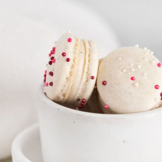 Vanilla bean macarons with pink sprinkles in a white bowl.