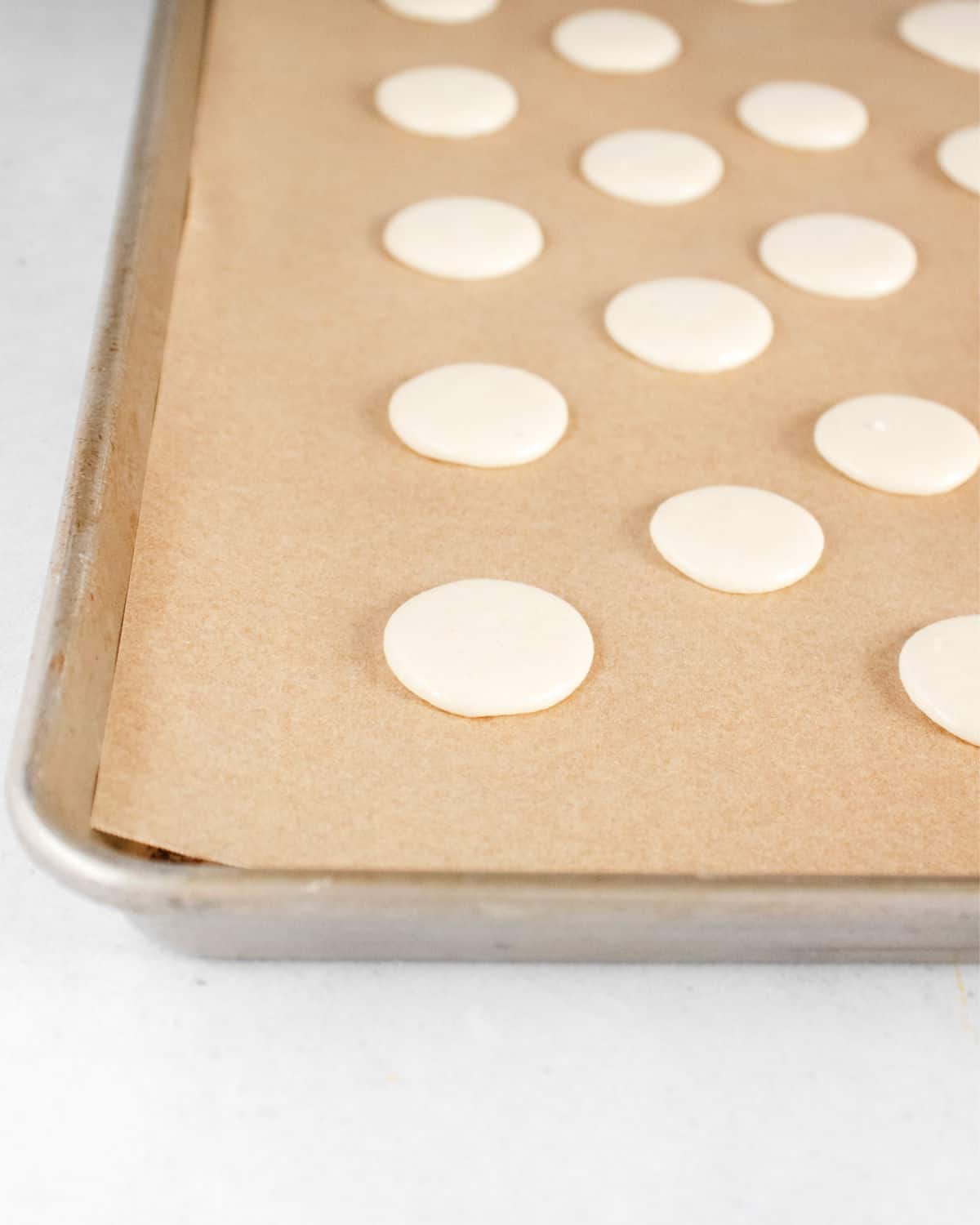 Macarons on baking sheet with parchment paper.