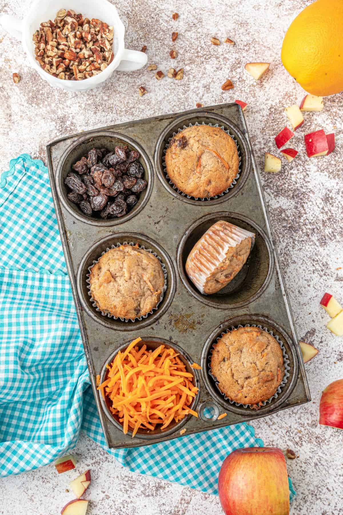 Morning glory muffins styled in a cupcake tin with shredded carrots and raisins.