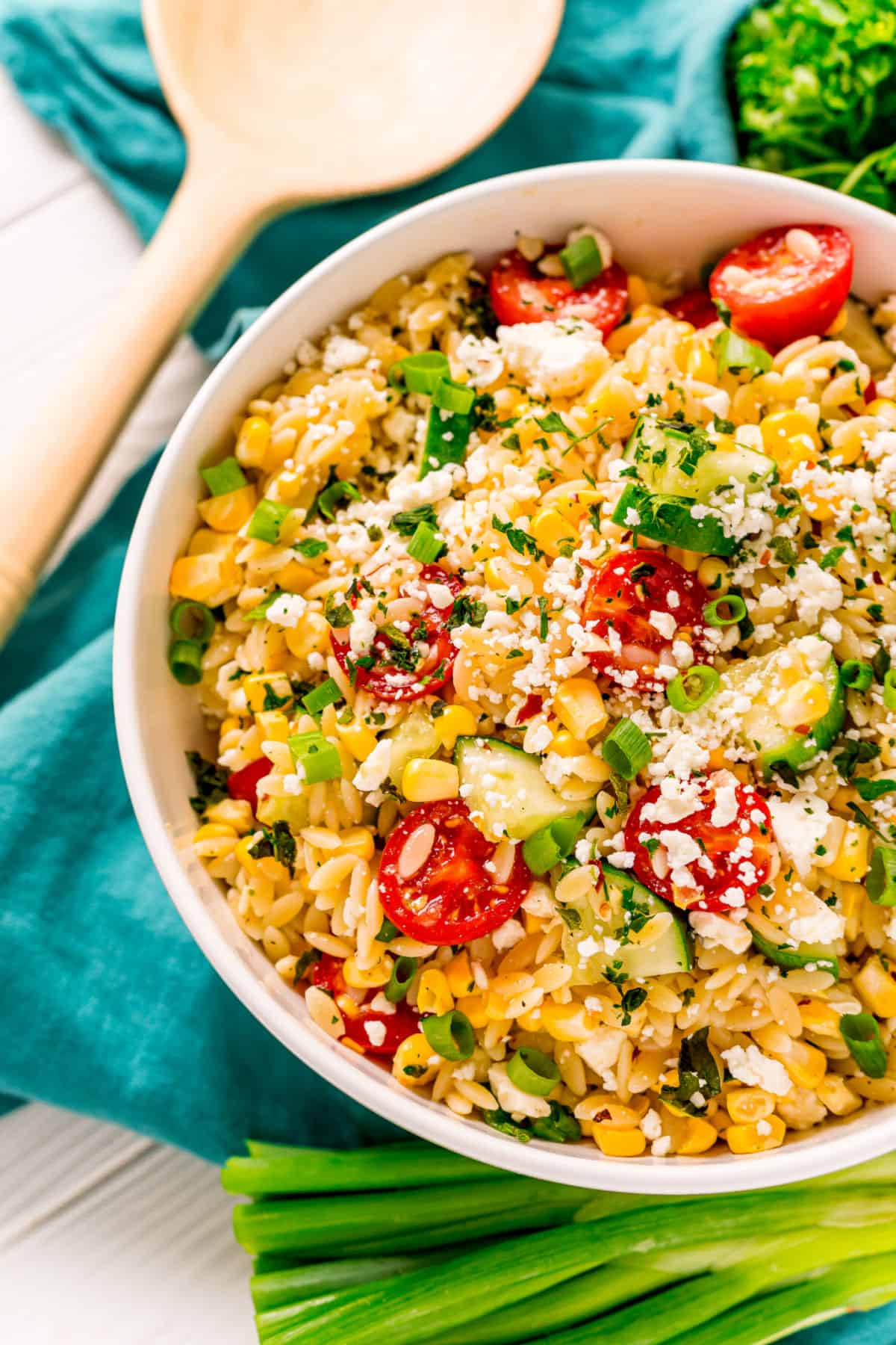 Pasta salad with orzo, corn, tomatoes, and cucumber in white bowl.