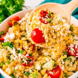 Orzo pasta salad with cucumbers and tomatoes in white serving bowl.