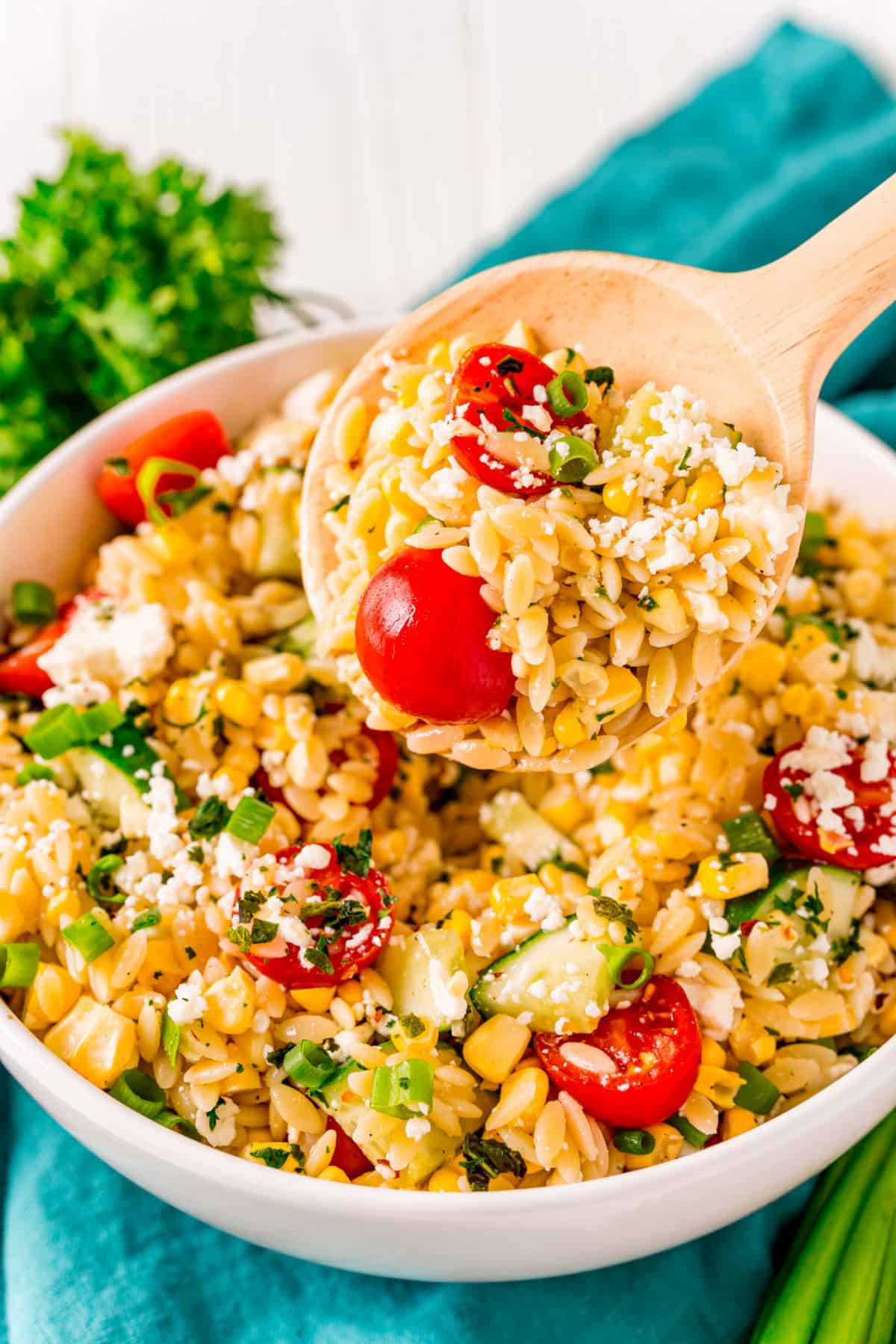 Orzo pasta salad with cucumbers and tomatoes in white serving bowl.