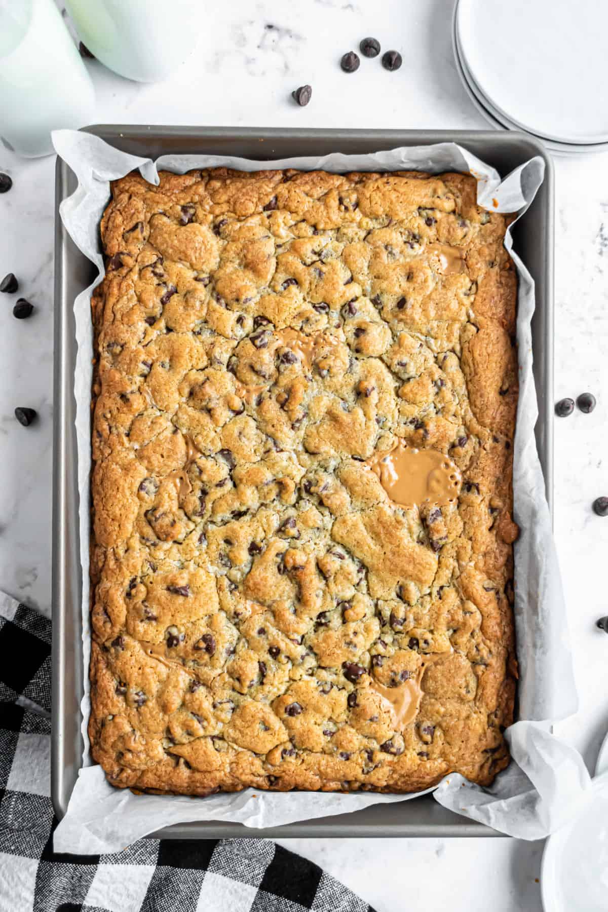 Baked peanut butter swirled chocolate chip cookie bars in a parchment paper lined 13x9 baking dish.