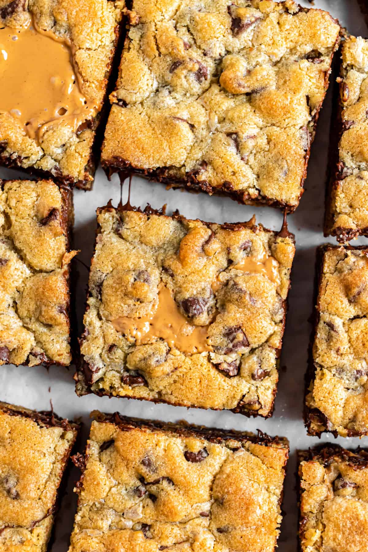 Chocolate chip peanut butter swirled cookie bars on a parchment paper lined baking sheet.