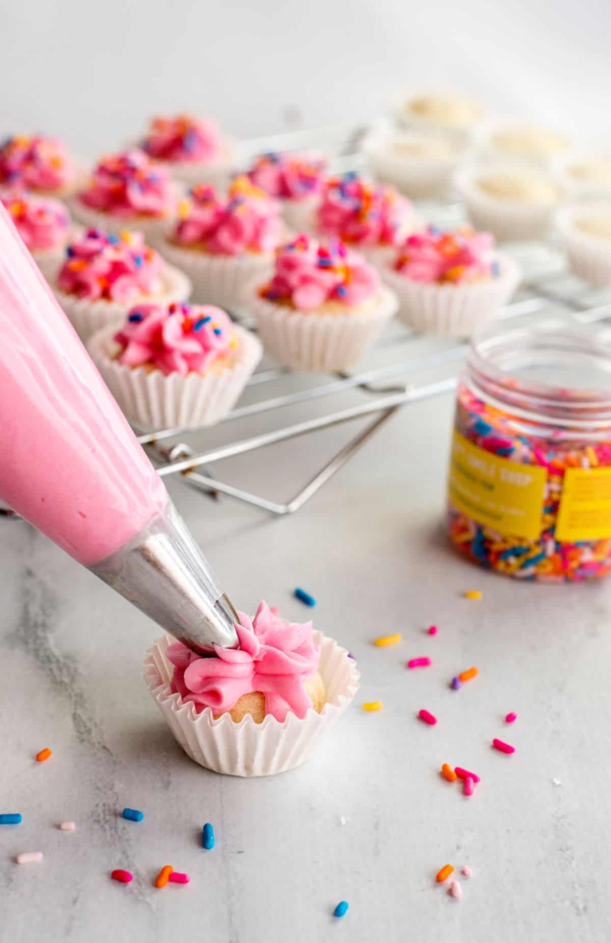 Sugar cookie bite being frosted with pink buttercream.