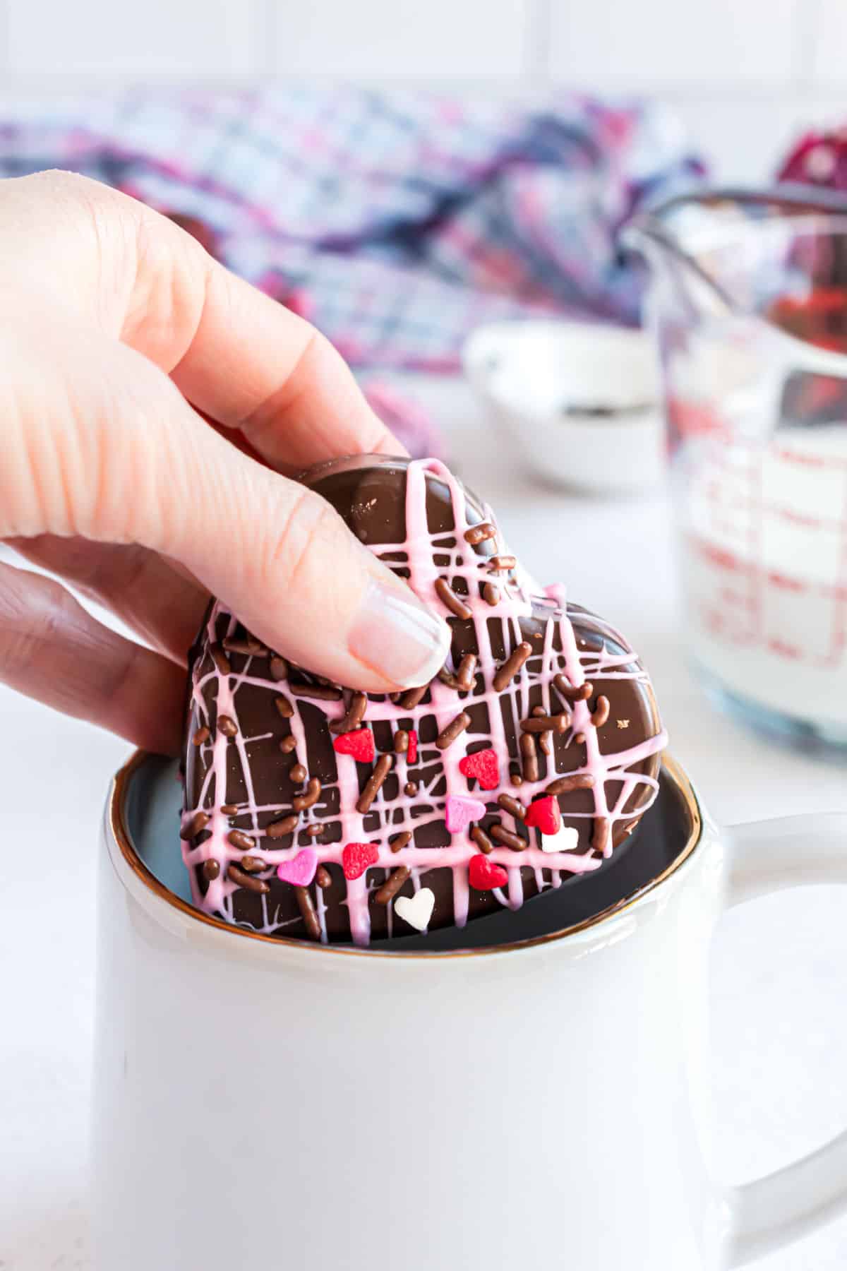 Valentine's hot cocoa bomb being placed in a mug for hot chocolate.