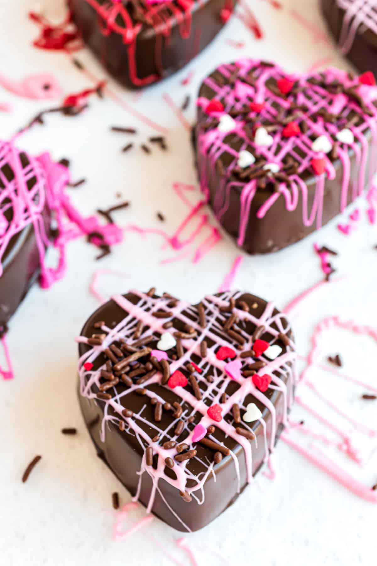 Heart shaped hot chocolate bombs with pink and red chocolate drizzle.