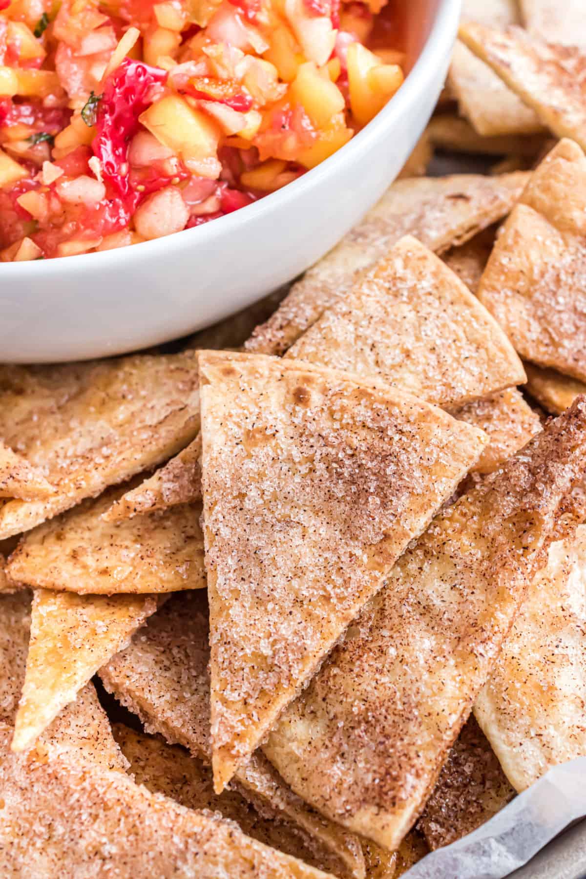 Baked cinnamon chips in a bowl with a side of fruit salsa for dipping.