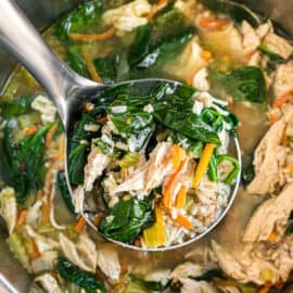 Chicken and rice soup with spinach being ladled out of the pressure cooker.