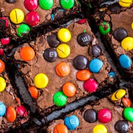 Squares of M&M brownies on a piece of parchment paper.