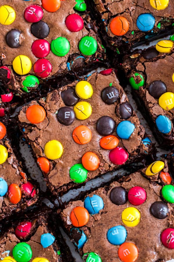 Squares of M&M brownies on a piece of parchment paper.