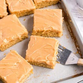 Peanut butter sheet cake sliced into squares on a baking sheet.