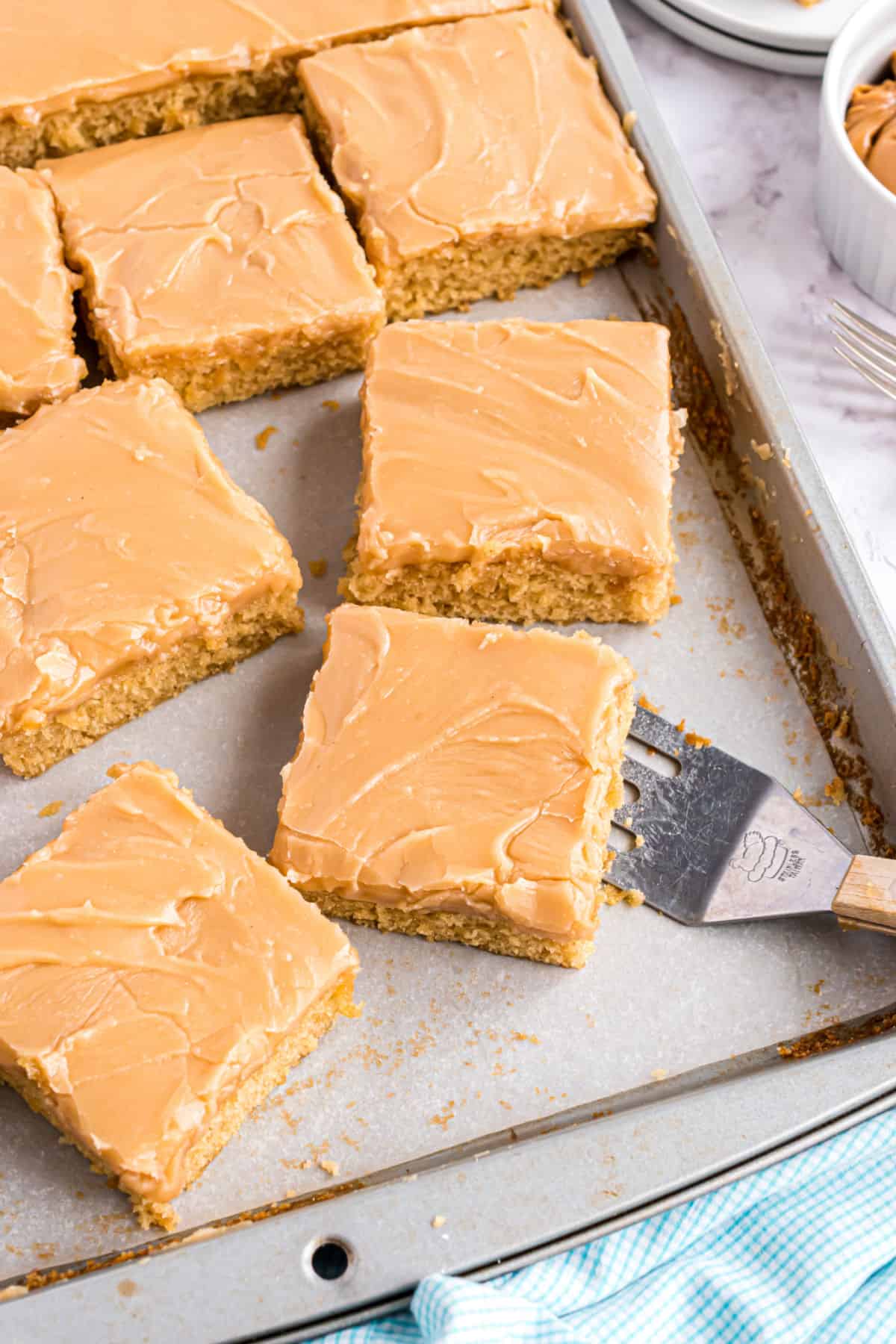 Peanut butter sheet cake sliced into squares on a baking sheet.