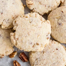 Pecan sandies stacked on baking sheet.