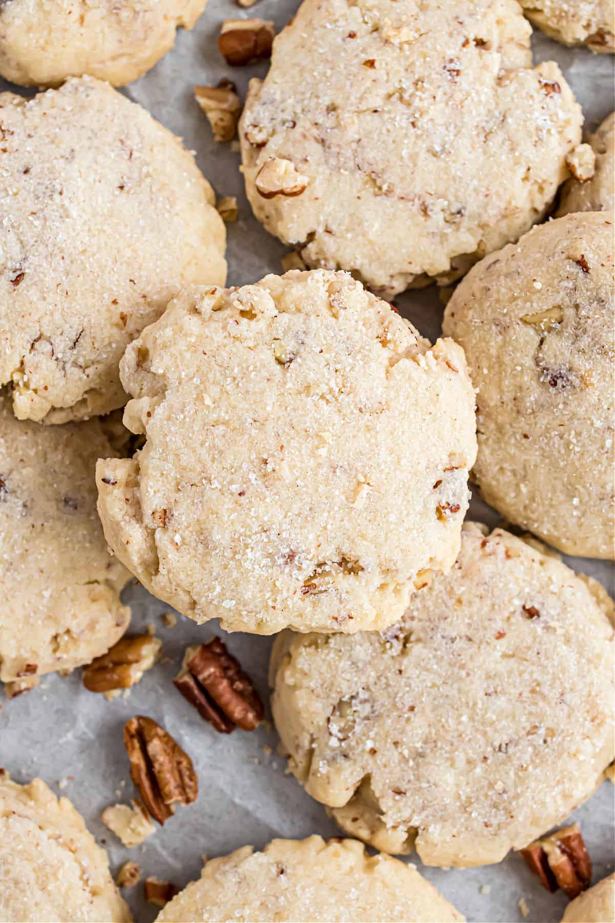 Pecan sandies stacked on baking sheet.