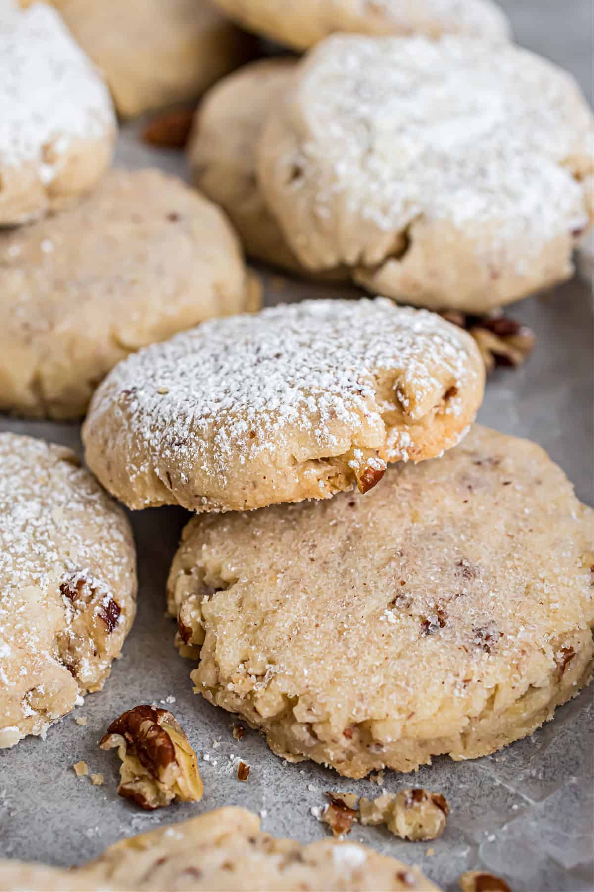 Pecan sandies on cookie sheet, some dusted with powdered sugar.