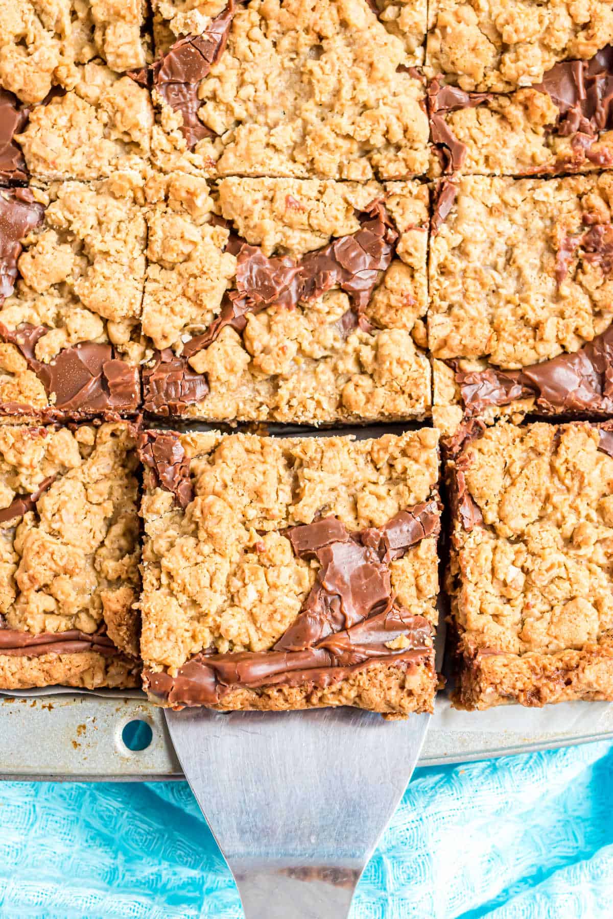 Oatmeal cookie bars in sheet pan with spatula removing one square.