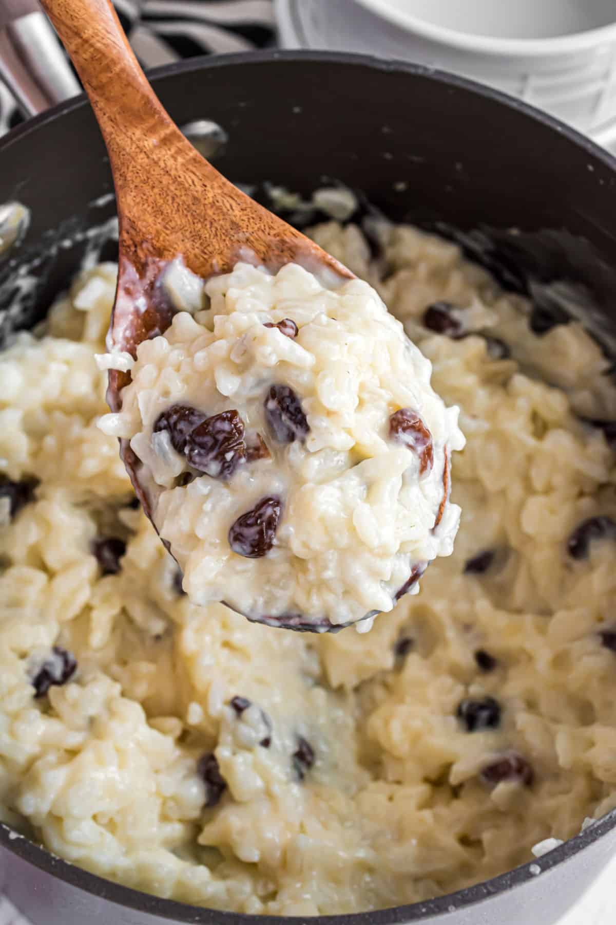 Rice pudding with raisings being spooned out of saucepan.