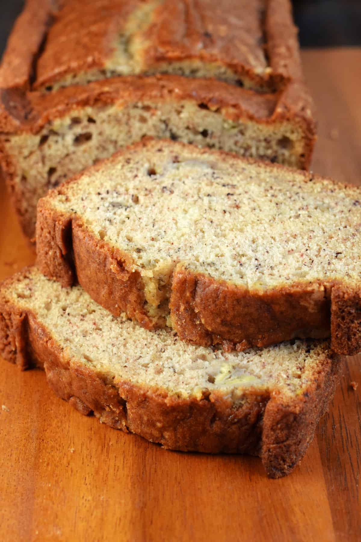 Two thick slices of banana bread on a wooden cutting board.