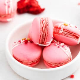 Strawberry macarons in a white bowl.