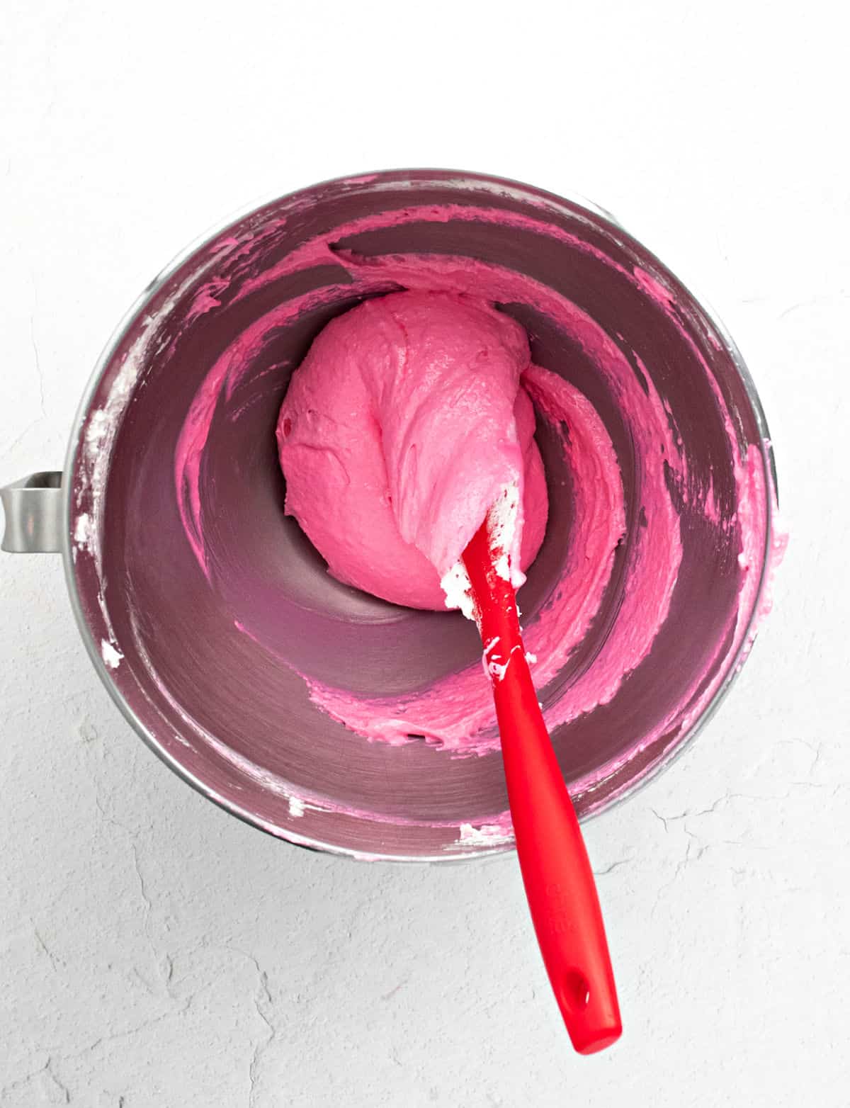 Strawberry macaron shell batter in a metal mixing bowl.