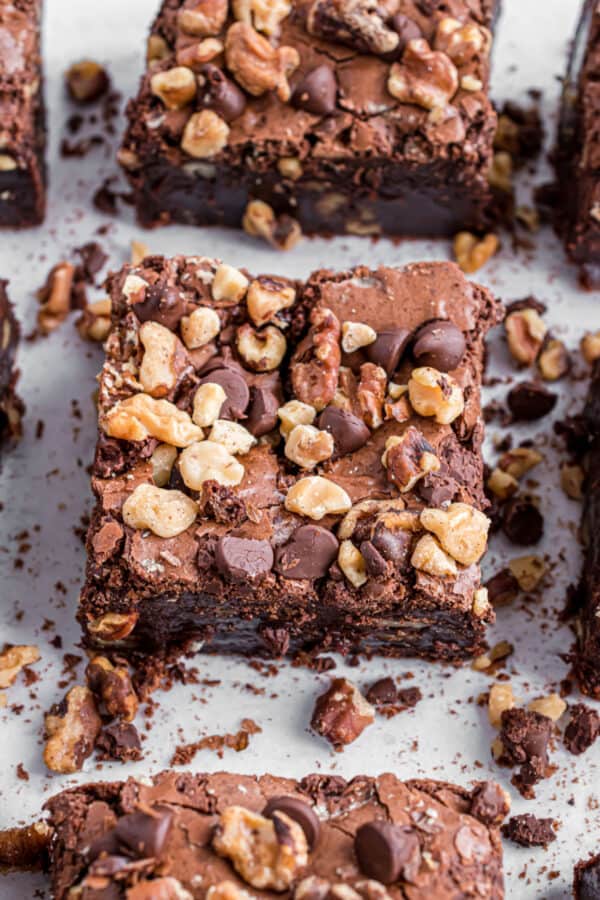 Walnut brownies cut into squares on parchment paper cookie sheet.