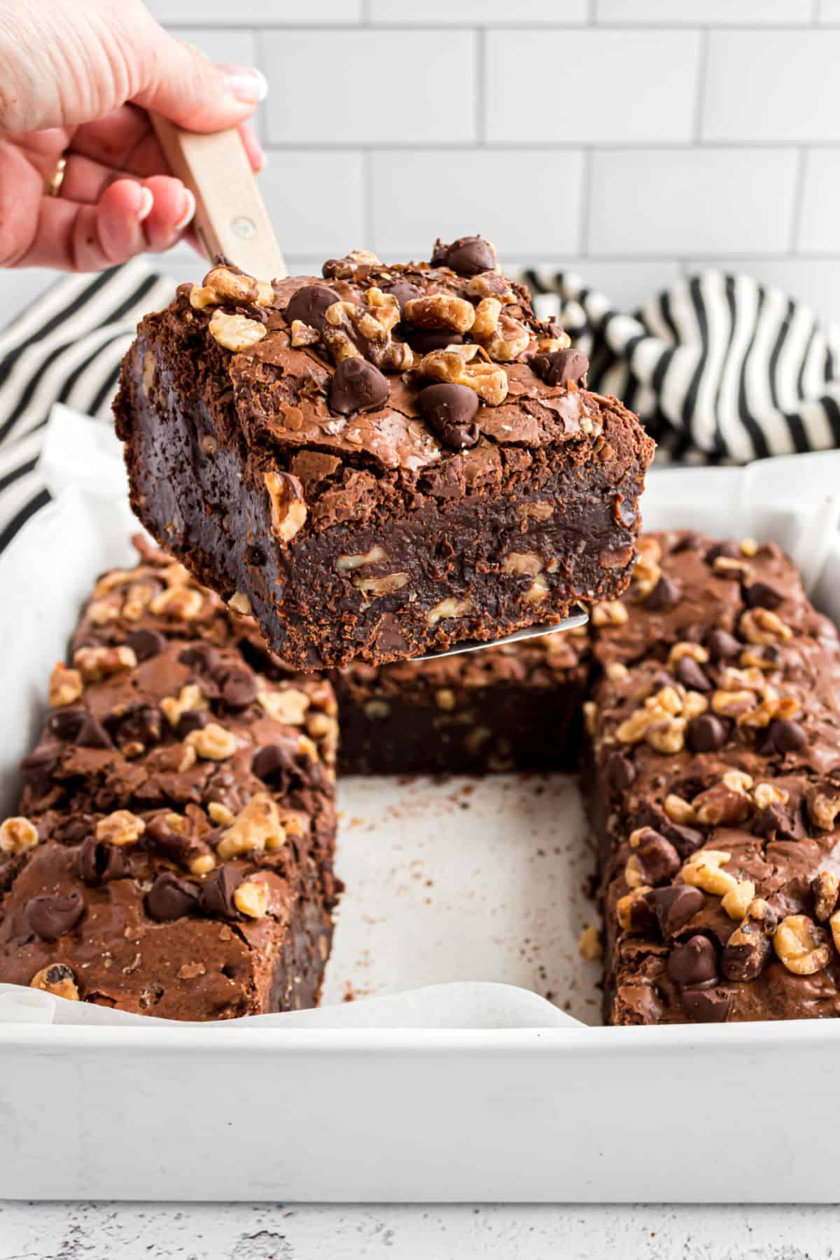 Chocolate walnut brownie being lifted out of the pan with a spatula.