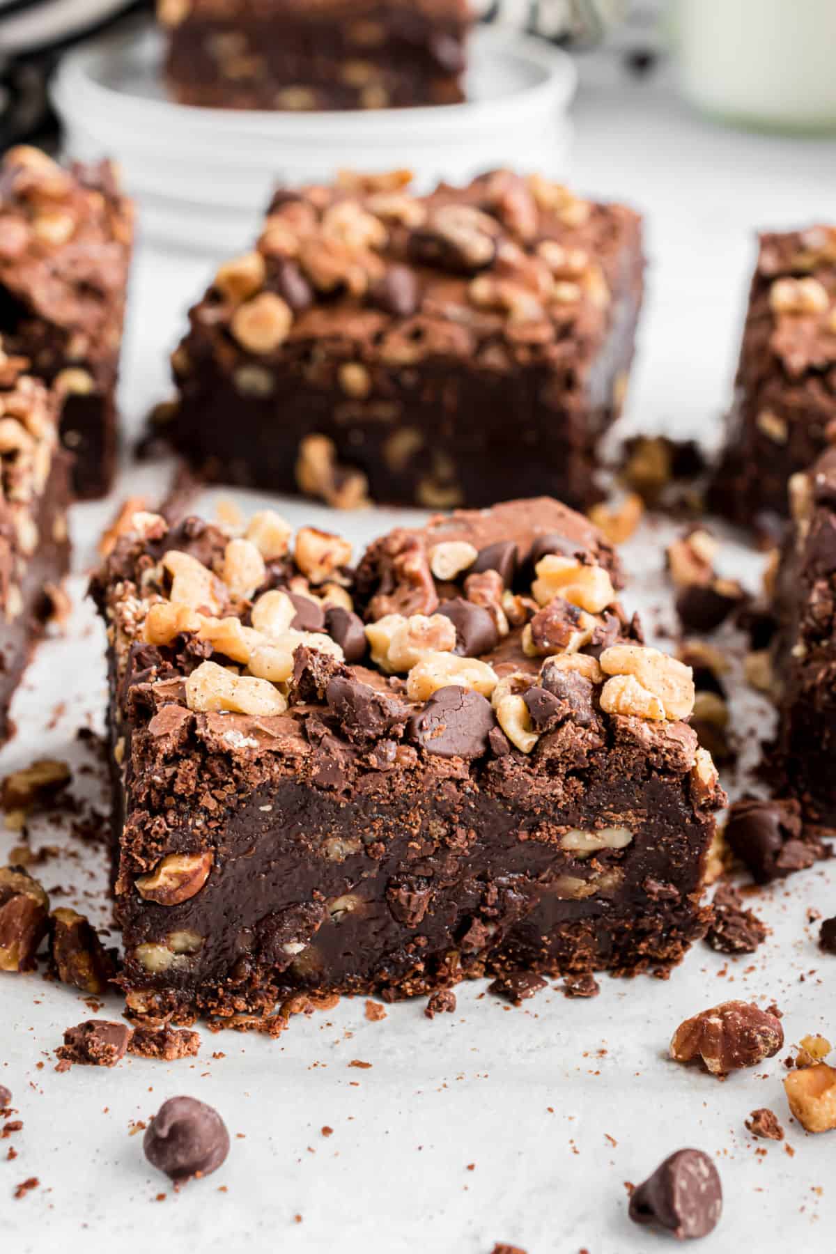 Square of thick, fudgy brownie packed with walnuts on a piece of parchment paper.