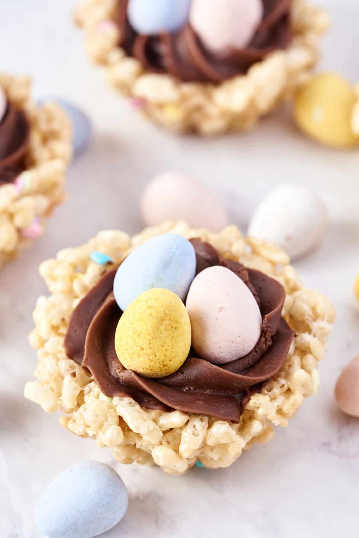 Rice krispie treats shaped as a nest and filled with chocolate frosting and candy.