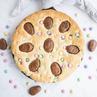 This Sugar Cookie Cake has everything you love about your favorite cut out treats, only it's baked as one GIANT cookie the size of a cake. M&Ms and peanut butter cups make this cookie cake even better. Perfect for holidays and only 5 ingredients!