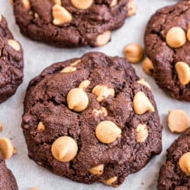 Chocolate cookies with peanut butter chips on a parchment paper lined cookie sheet.