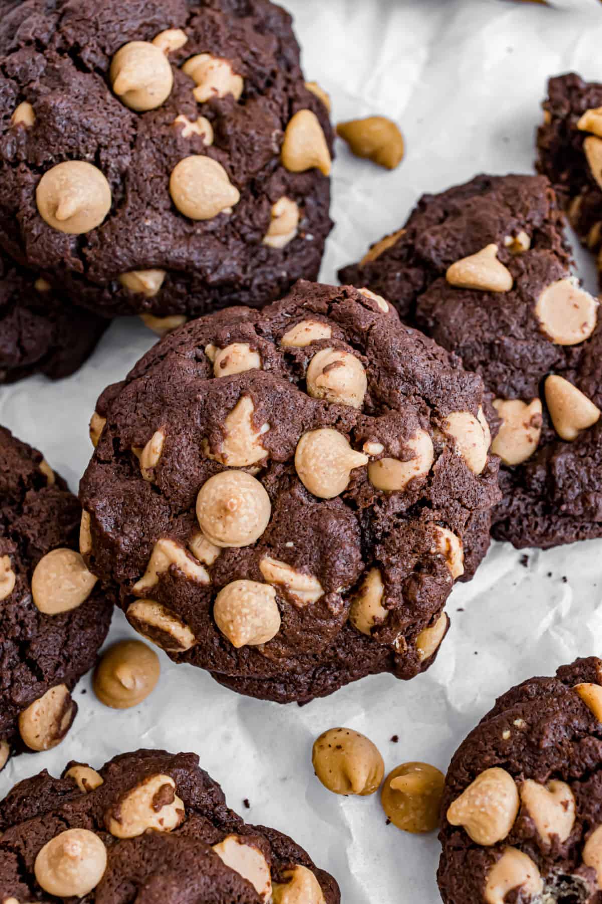 Chocolate peanut butter cookies stacked on parcment paper.