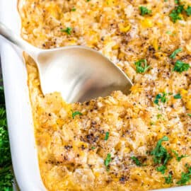 Corn casserole garnished with parsley in a white baking dish.