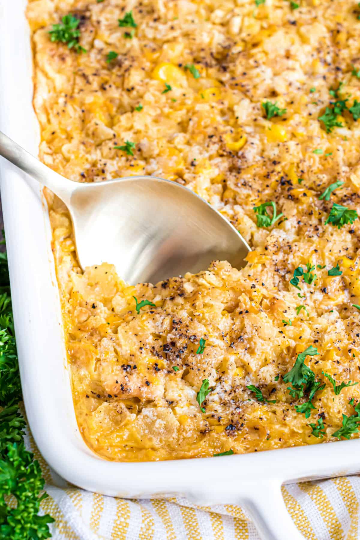 Corn casserole garnished with parsley in a white baking dish.