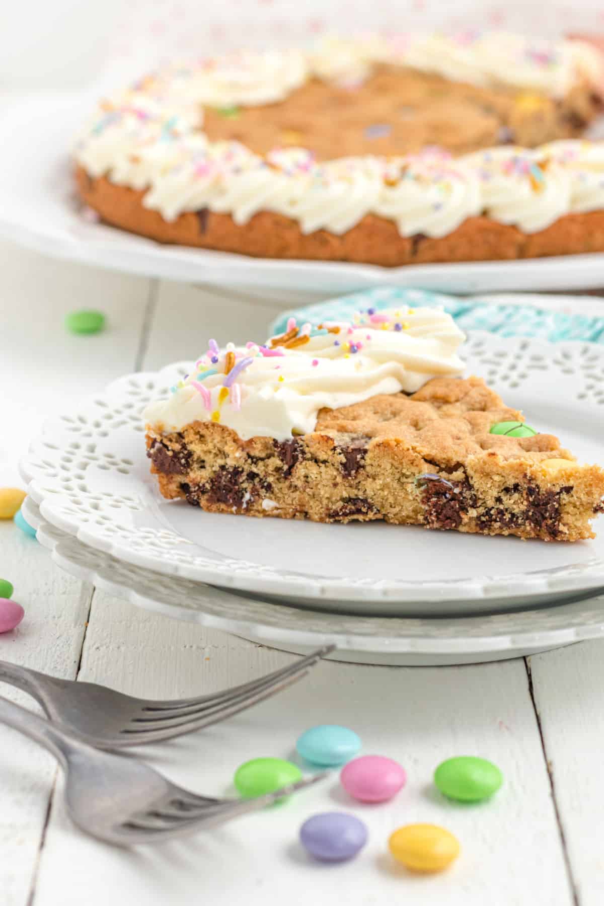 Slice of chocolate chip cookie cake on a white plate.