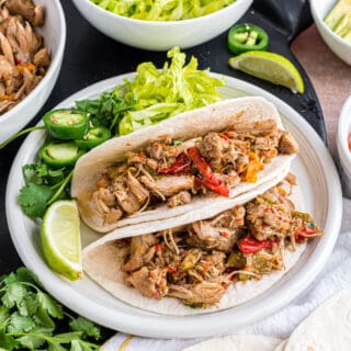 Chicken fajitas on flour tortillas with toppings on side.